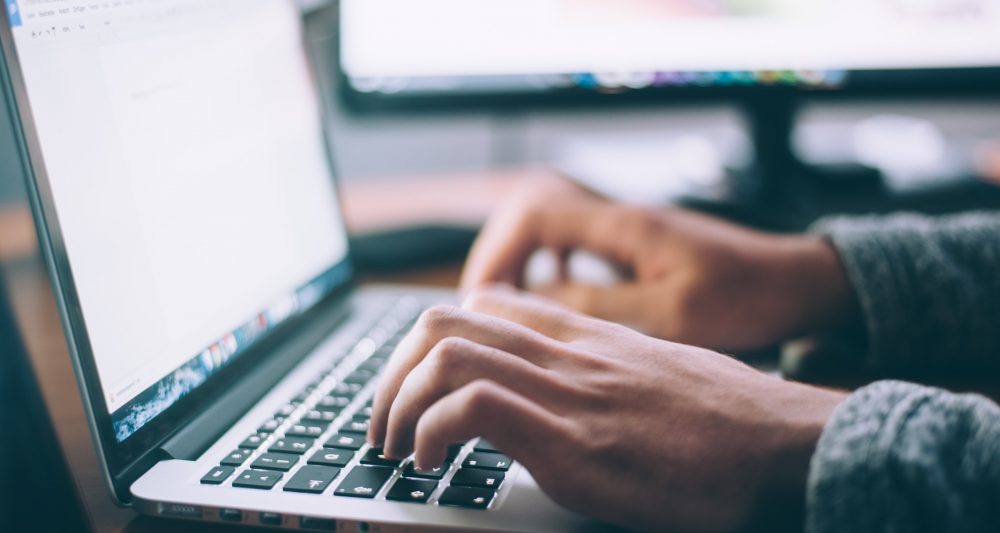 A laptop with a hands tapping