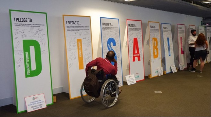 Global Disability Summit room: a person in a wheelchair looking some posters 