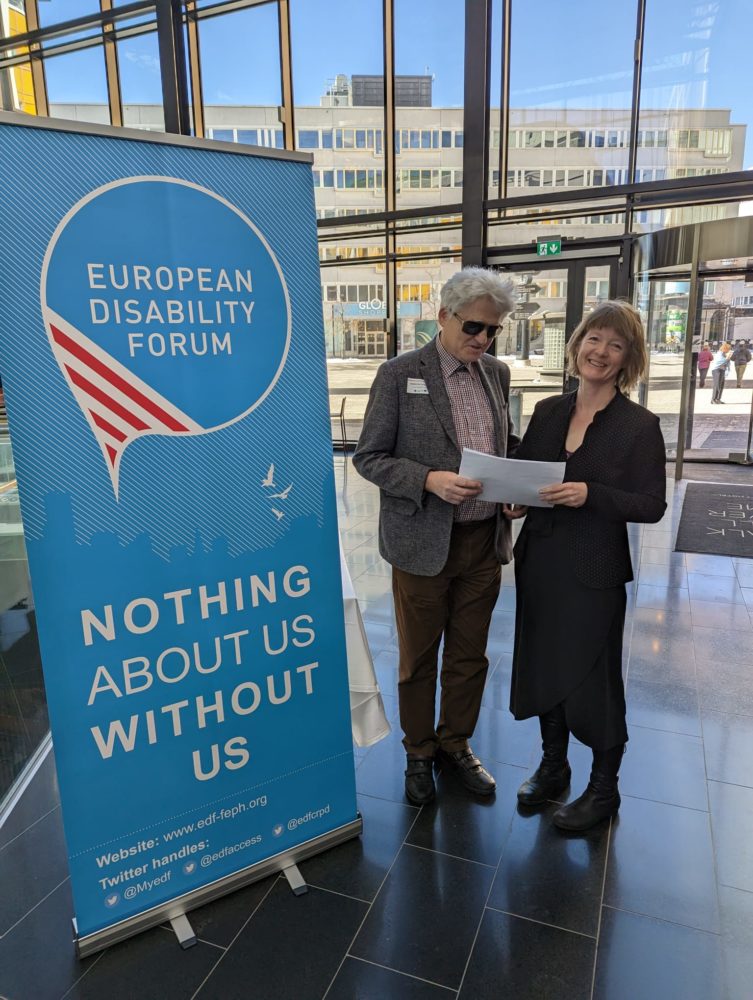 Two people smiling and signing a contract in front of an EDF banner 