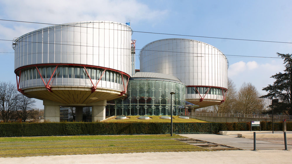Two round buildi,gs made of metal with a futuristic look. they are slightly above groound and are connected by a glass round building on the ground
