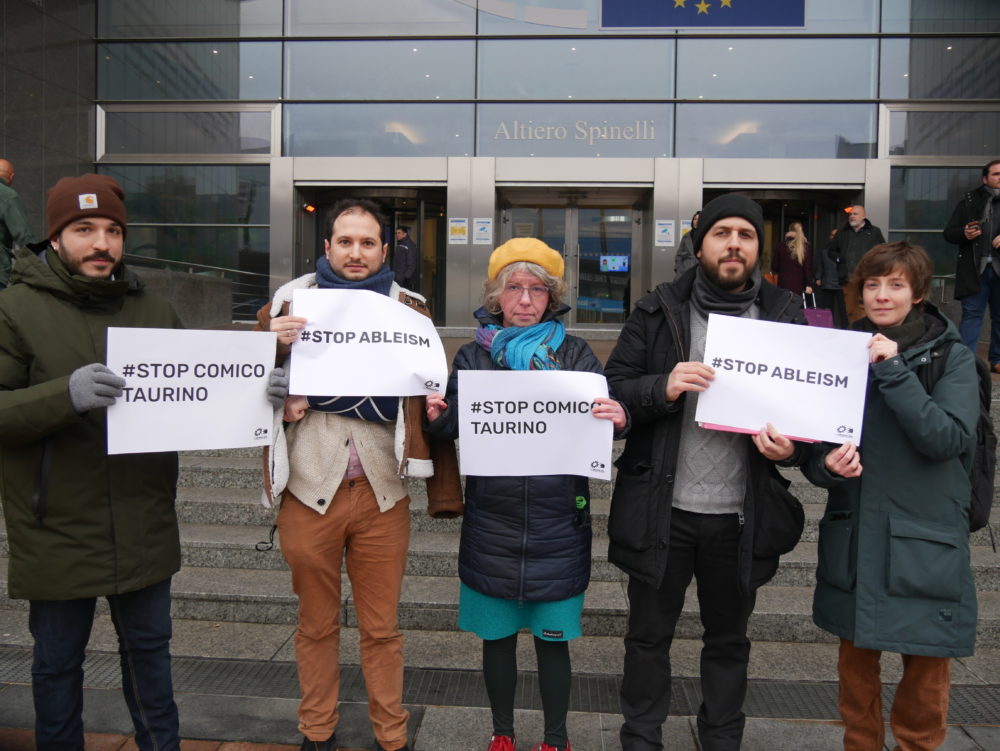 MEP Katrin Langensiepen EDF team standing in front of the European Parliament and holding paper signs saying #Stop Comico Taurino and #Stop Ableism