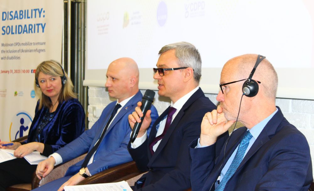 High-level panel: four people sitting, one is talking