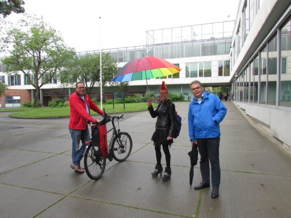 Jolijn holding a rainbow umbrella with two colleagues