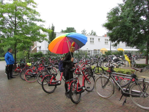 Jolijn in a bike parking holding a rainbow umbrella