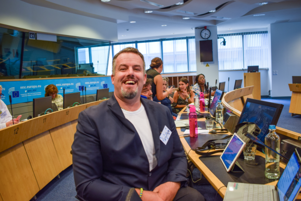 Soufiane El Amrani wears a suit and smiles, sitting in a conference room at the European Parliament.