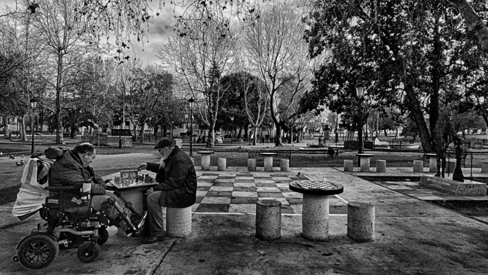 Sport for all. Two elderly men are playing chess in a park. The table is adapted so that everyone can play. It’s a great example of accessibility in public spaces.