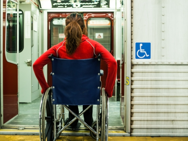 A young woman in a wheelchair enters a train that is aligned with the platform, without the need for a ramp.