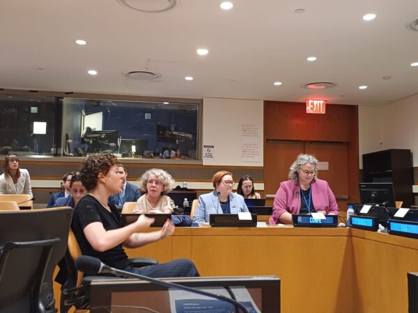 Speakers sit at a desk facing a sign interpreter