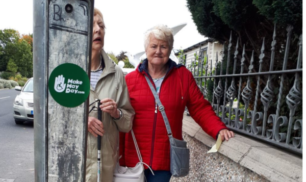 Two older women walked in the sidealk and are blocked by a lamp post