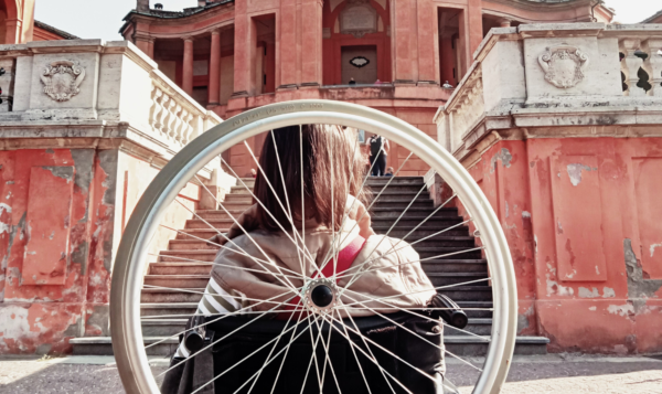 A young woman in a wheelchair faces steps in front of a monumental red church