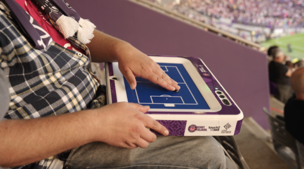 A blind football fan uses a tactile version of the field during a match